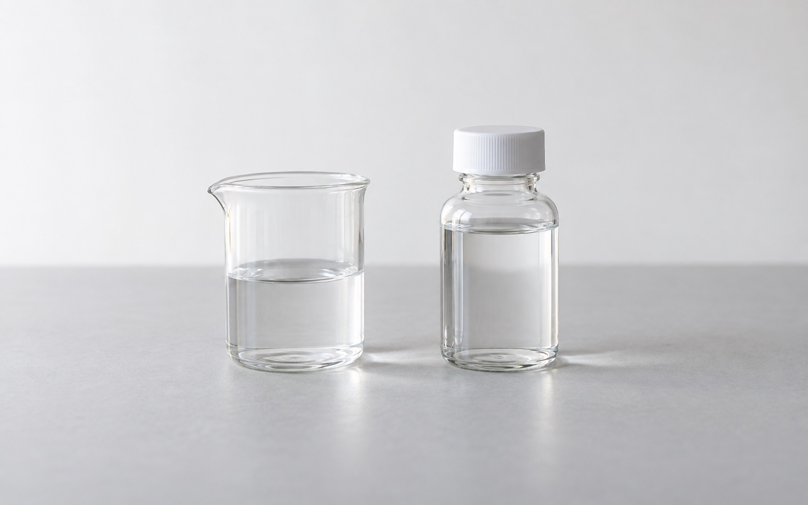 Illustrative laboratory still life with a plain glass beaker and capped sample bottle.